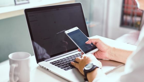 graphicstock-businessman-hand-using-smart-phone-and-keying-the-data-to-laptopclose-up-seleted-focus_H_UIInDlog